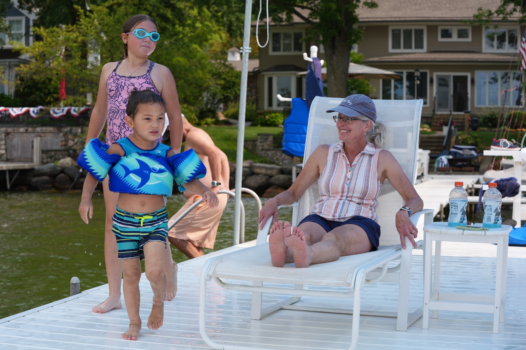 Children walking past their grandmother relaxing at the dock