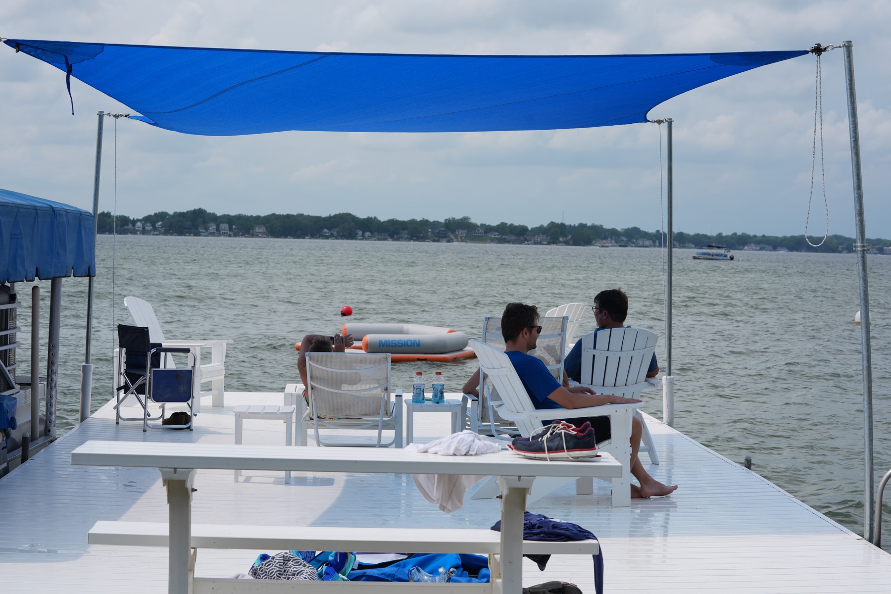 Friends seated beneath a blue DockShade with the lake ahead
